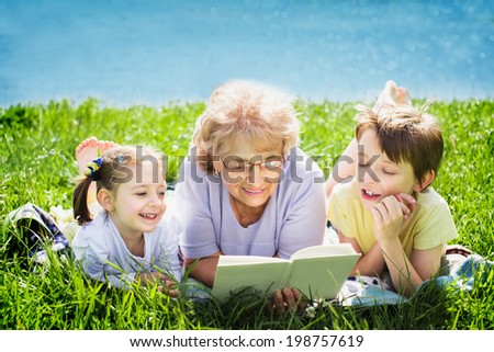 Grandmother reading a book for grandchildren, outdoors