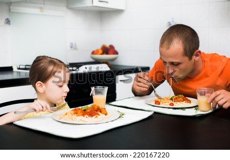 father with daughter eating pasta with sauce for the dinner