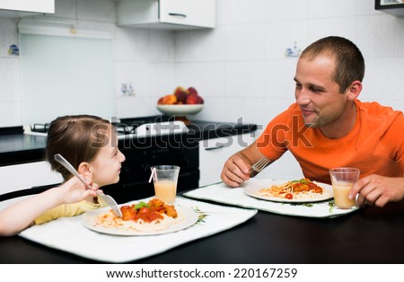father with daughter eating pasta with sauce for the dinner