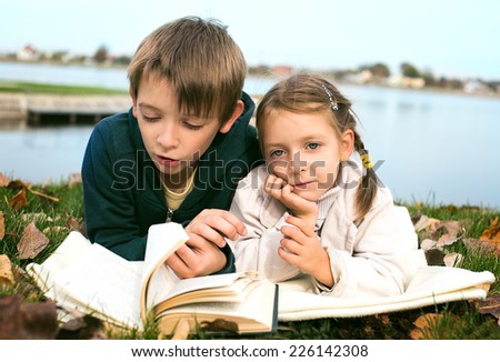 Kids reading together enjoying a book outdoors