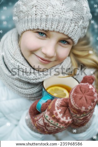 closeup winter portrait of a cute girl with a cup of hot tea outdoors