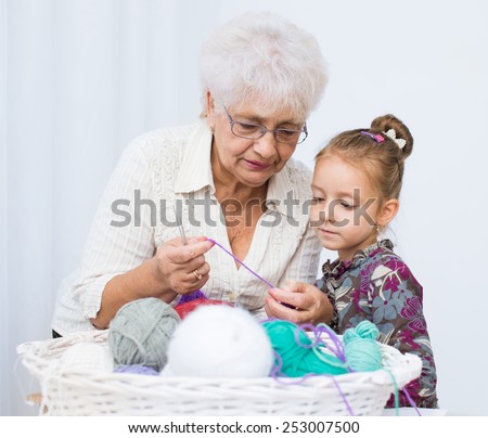 cute little girl and her granddaughter knitting together