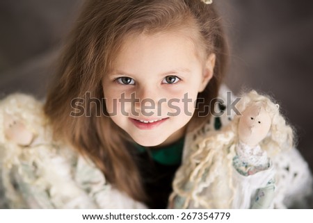 portrait of a cute little girl playing with her textile handmade princess dolls