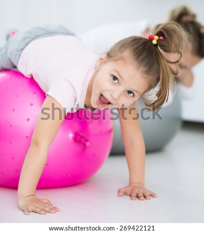 Mother with daughter doing gymnastic exercises with balls