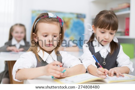 Portrait of two little girls looking at camera at workplace with children on background
