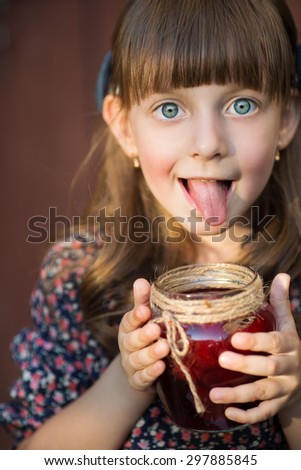 Portrait of a cute little girl eating sweet homemade jam with berries