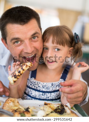 Portrait of happy father with child eating pizza