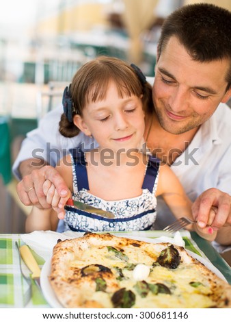 Portrait of happy father with child eating pizza