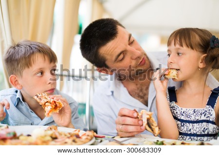 Portrait of happy father with children eating pizza