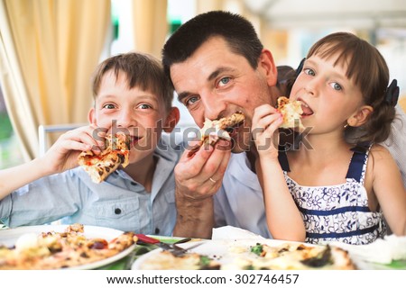 Portrait of happy father with children eating pizza