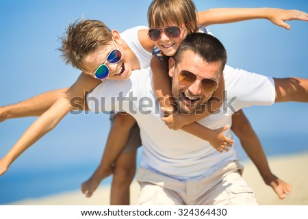 Father with children having fun on the beach at the day time.