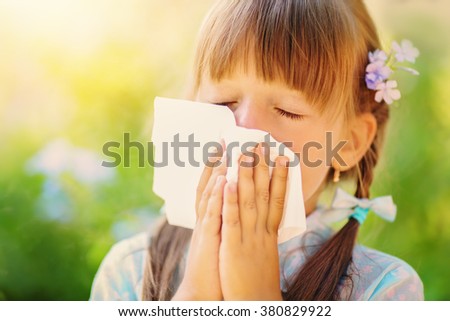 spring portrait of a little girl is blowing her nose