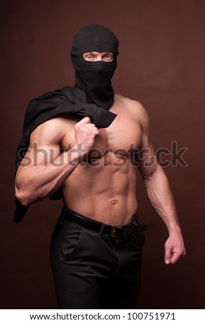 Casualy dressed model in a mask taking of his shirt
