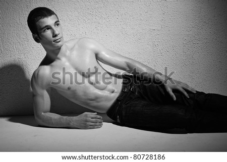 portrait of muscular young man, black and white studio background.
