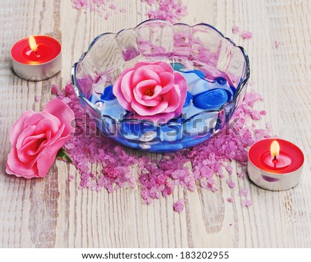 Soap in form of roses in bowl of water on wooden background. Closeup.