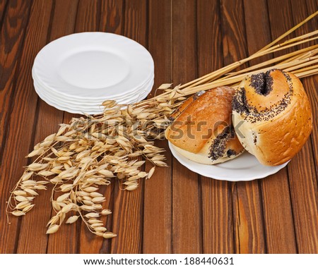 French buns with poppy seeds on saucer plate on wooden background.