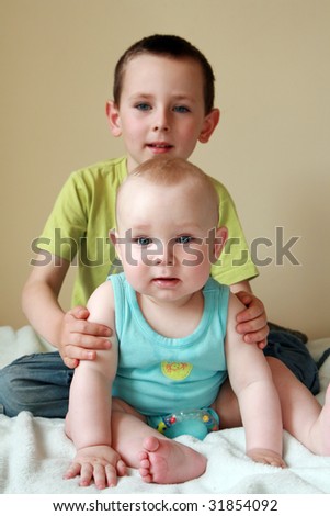 Portrait of two brothers. 7 months old baby boy and 5 years old preschooler. Two kids smiling and having fun.