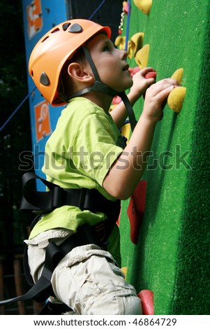 5 years old child climbing on a wall in an outdoor climbing center