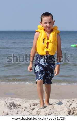 Six  years old  boy wearing in life jacket and learning to swim in the sea.