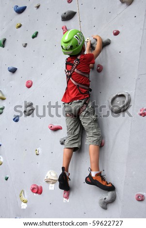 6 years old child climbing on a wall in a climbing center.