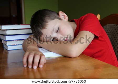 8 years old boy doing his boring homework and sleeping