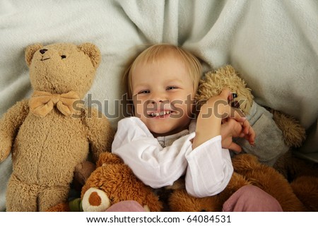Happy child in bed with teddy bear
