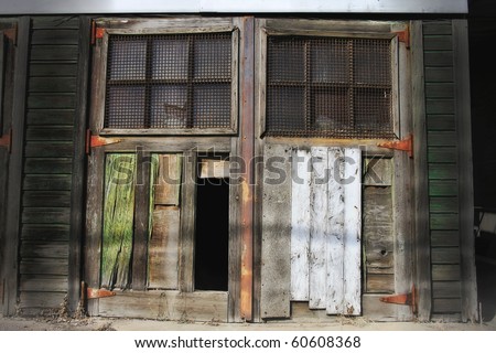 Old weathered door with a rusty grating and broken panel