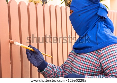 Construction worker is painting wooden fence