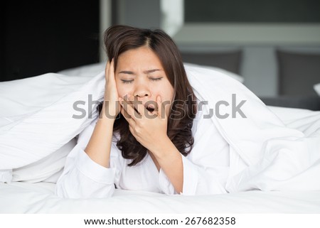 Sleepy asian woman yawning in bed at home