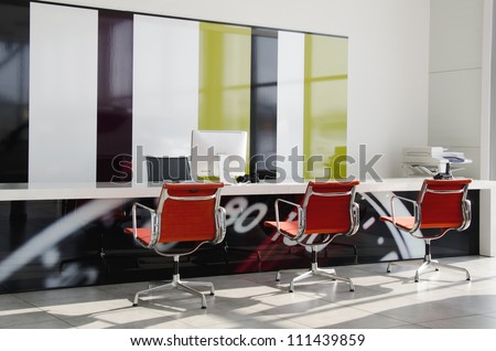 Modern office interior with red chairs and white furniture