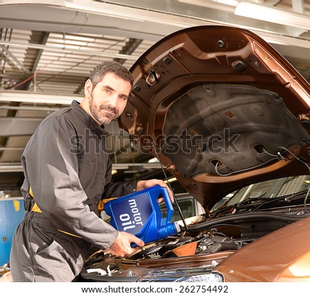 Repairman auto mechanic inspecting and refilling engine with motor oil during automobile maintenance at engine auto repair shop service station