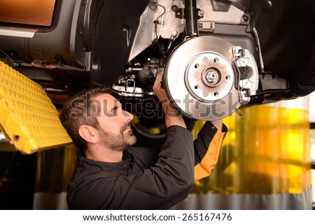 Car mechanic checking car at auto repair shop service station, front or rear axle inspection