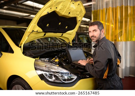 Car mechanic checking car at auto repair shop service station, motor management inspection with special computer unit