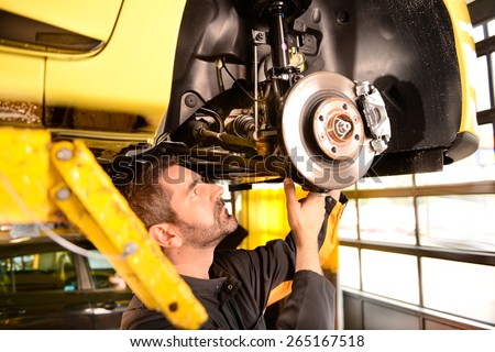 Car mechanic checking car at auto repair shop service station, axle and suspension inspection