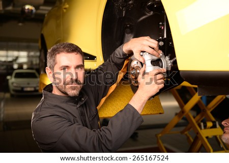 Car mechanic checking car at auto repair shop service station, brake pad and disc control