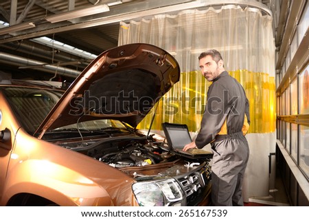 Car mechanic checking car at auto repair shop service station, computer control