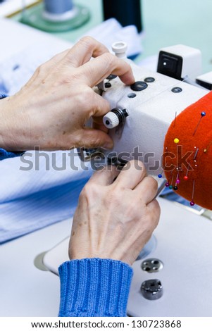 Hands work a sewing machine.