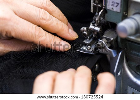 Hands work a sewing machine.