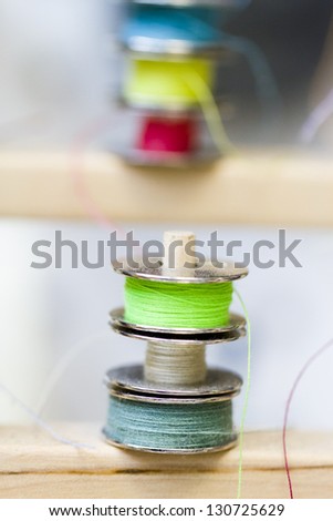 Colorful bobbins of thread on bobbin stand in tailor shop.