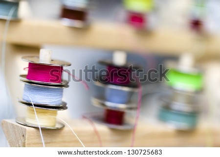 Colorful bobbins of thread on bobbin stand in tailor shop.