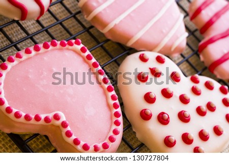 Gourtmet heart shaped cookies decorated for Valentine's Day on drying rack.