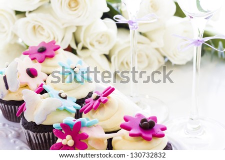 Miniature cupcakes decorated with bright flowers for the wedding party.