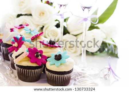 Miniature cupcakes decorated with bright flowers for the wedding party.