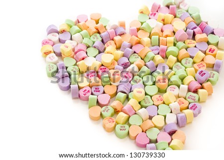 Pile of conversation heart candies in heart shape.