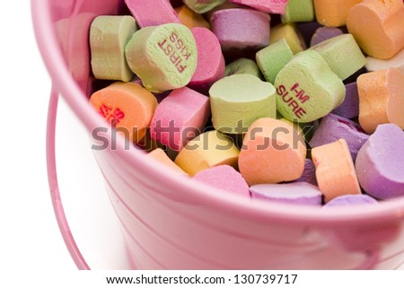 Conversation heart candies in pink bucket.