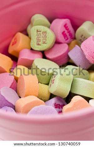 Conversation heart candies in pink bucket.