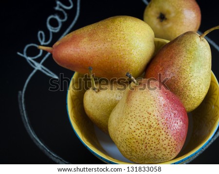 Ripe pear on black background. The cultivation of the pear in cool temperate climates extends to the remotest antiquity, and there is evidence of its use as a food since prehistoric times.