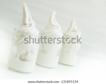 Frozen soft-serve yogurt in glass on white background.
