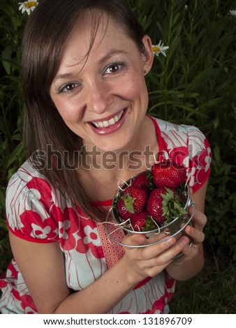 Portrait of a smiling young woman holding strawberries.