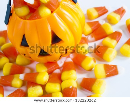 Halloween treat bag filled with candy corn candies on white background.